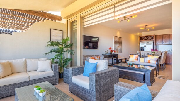 Un espace de vie moderne avec des meubles en osier, une table basse en verre et un coin repas comprenant une table et des chaises.