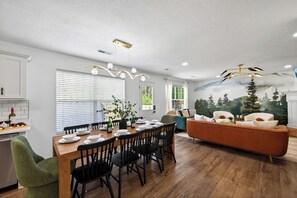 Eine moderne Küche mit Essbereich, ein Wohnzimmer mit Sofa und ein Wandgemälde an der Wand.