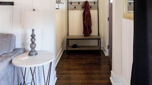 Una habitación con un banco de madera, una lámpara, un perchero y un espejo.