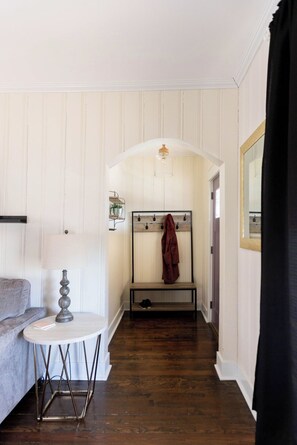 A room with a wooden bench, a lamp, a coat rack, and a mirror. - Full Home Available for WORLD CUP! (Kansas City)