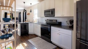 Una cocina moderna con armarios blancos, un microondas negro, una estufa y un refrigerador.