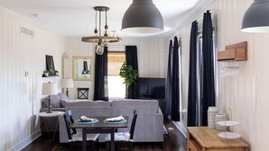 Una sala de estar moderna con comedor, televisor y cocina con encimeras de granito.