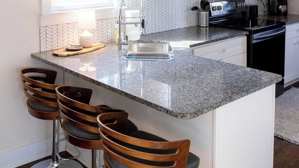 Una cocina con una isla grande, taburetes de bar, lámparas colgantes y electrodomésticos modernos.