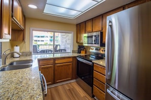 A kitchen with wooden cabinets, a stainless steel refrigerator, a microwave, and a dishwasher. - Lagoon Views; Community Pool, Hot Tub & Cabana; Dog-Friendly; Walk to Shelter Cove Marina & Shops! (Hilton Head Island)