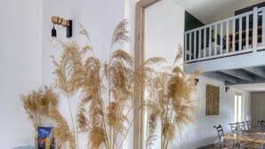 A room with a dining table, chairs, a mirror, and decorative dried plants. - Villa Ambre - BULLY - Gîte (BULLY)