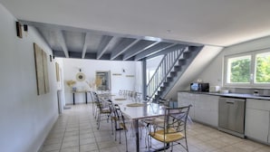 A spacious kitchen with a dining area, a staircase, and a view of greenery outside. - Villa Ambre - BULLY - Gîte (BULLY)