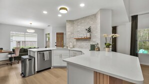 Una cocina moderna con encimera blanca, horno empotrado y mueble de madera.