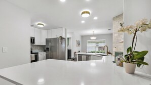 Una cocina moderna con armarios blancos, electrodomésticos de acero inoxidable y una isla central.