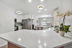 A modern kitchen with white cabinetry, stainless steel appliances, and a central island. - Blissful Retreat Savannah/PET Friendly/3 BD/2 BATH (Savannah)