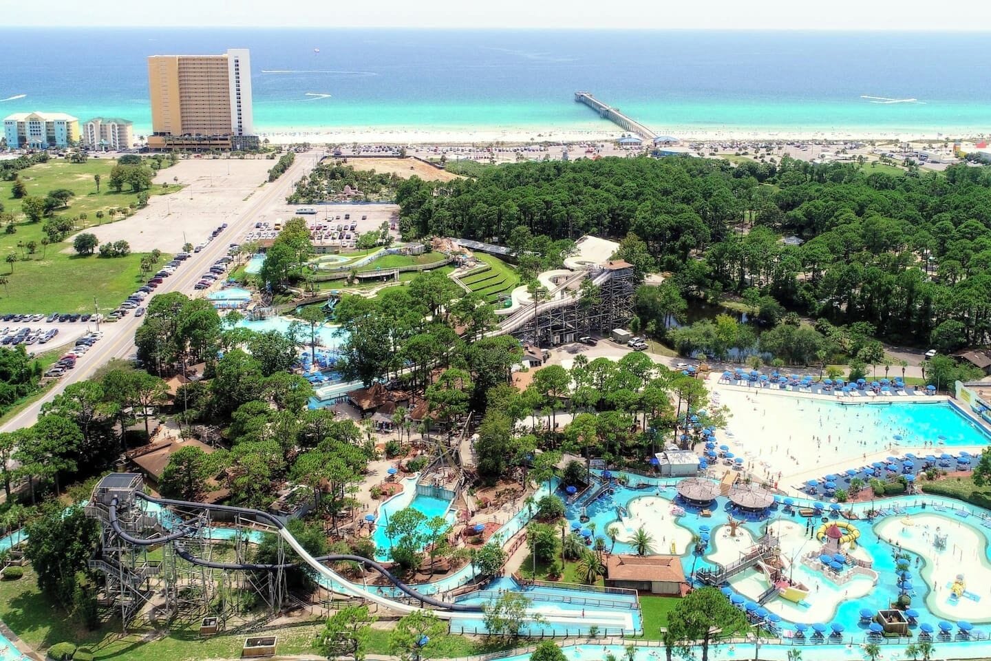 An aerial view of a resort with a large water park, a beach, and a pier.