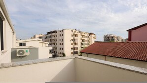 Ein Wohngebäude mit mehreren Balkonen, einem roten Ziegeldach und blauem Himmel.