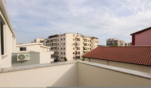 A residential building with multiple balconies, a red-tiled roof, and a clear sky. - Cozy Apartment 04 in Durr s (Durrës)