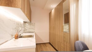 Eine moderne Küche mit Marmorarbeitsplatten, einem Edelstahlspülbecken, Holzschränken und einem eingebauten Backofen.