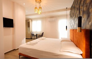 Ein Hotelzimmer mit Bett, Fernseher, Essecke und einem Gemälde an der Wand.