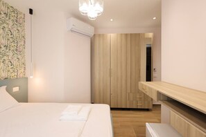 Quarto de hotel moderno com cama, guarda-roupa e um banco embutido.