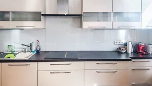 Une cuisine moderne avec des meubles blancs, un plan de travail noir et des appareils en acier inoxydable.