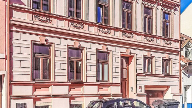 Un immeuble à plusieurs étages, de style architectural classique, caractérisé par des fenêtres disposées de manière symétrique et des moulures décoratives.