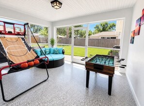 Ein Zimmer mit Basketballkorb, Kicker und einer Couch.