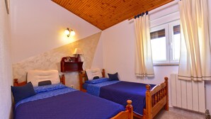 Una camera da letto con due letti, un soffitto in legno, un comodino con una lampada e una finestra con tende.