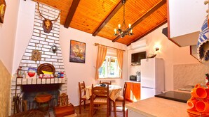 Una cucina accogliente con camino, soffitto in legno e zona pranzo con sedie e tavolo.