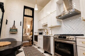 A kitchen with white cabinets, stainless steel appliances, and a black countertop. - The Estelle Walk to OTR, Convention Center and All (Cincinnati)
