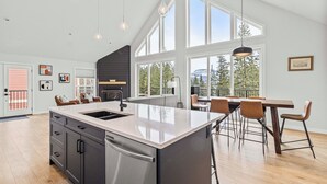 A spacious kitchen with a large island, modern pendant lights, and a view of the outdoors.