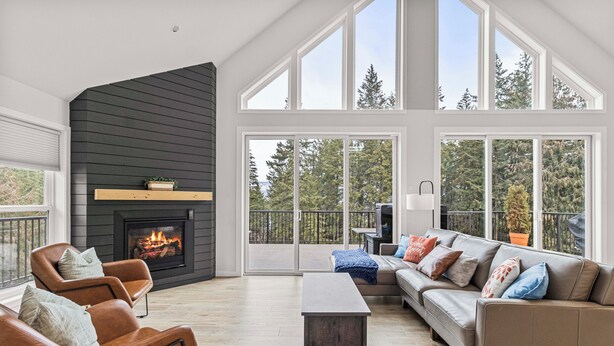 A spacious living room with a fireplace, large windows, a sofa, and a coffee table.