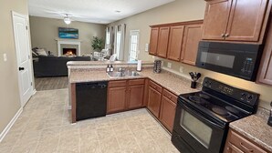 Una cocina con armarios de madera, lavavajillas, estufa y microondas.