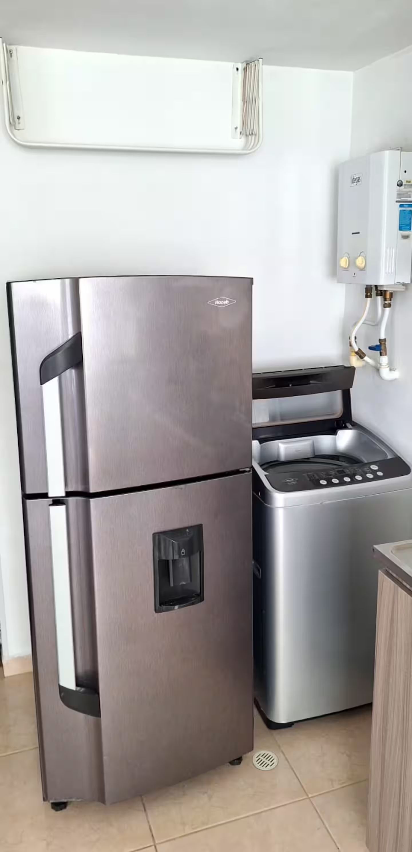 Eine kompakte Küche mit einem Edelstahl-Kühlschrank, einem eingebauten Backofen und einem Durchlauferhitzer.