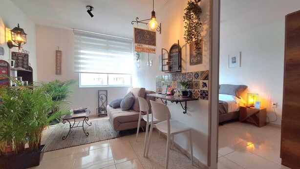 A cozy living room with a sofa, a coffee station, and a dining area.