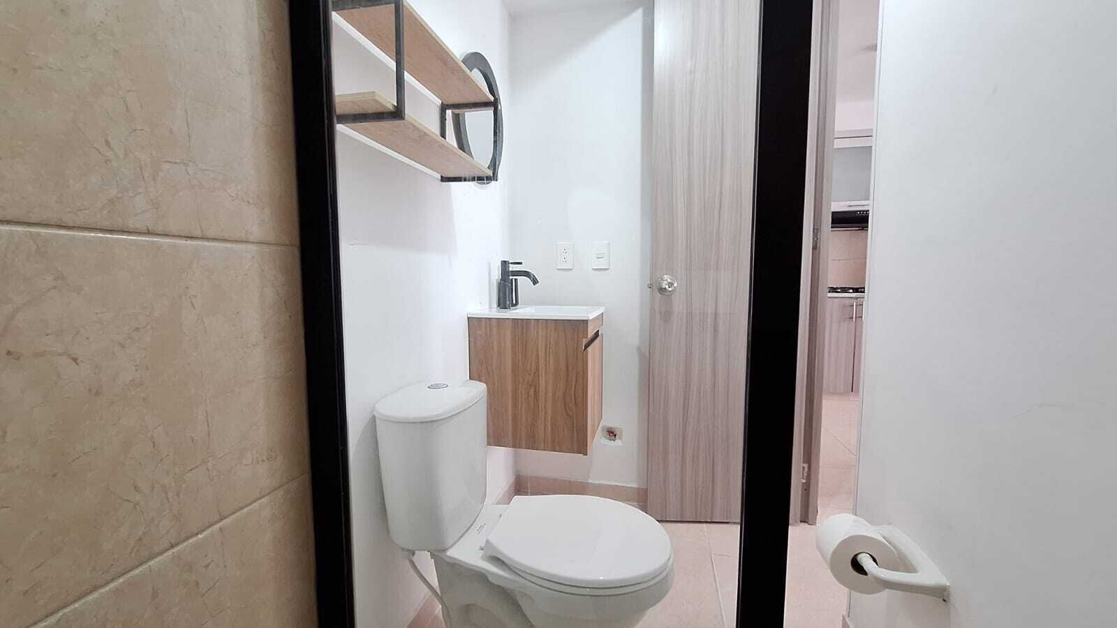 A bathroom with a toilet, sink, and wooden cabinet.