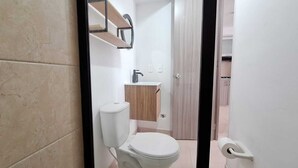 A bathroom with a toilet, sink, and wooden cabinet.