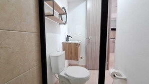 A bathroom with a toilet, sink, and wooden cabinet.