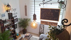A cozy cafe with a coffee station, a sign reading 'Caffe Puglia,' and a wall-mounted light fixture.