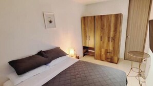 A bedroom with a bed, a bedside table, a lamp, a wardrobe, and a mirror.