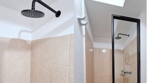 A bathroom with beige tiles, a shower with a black head, a glass-enclosed shower, and a white sink with a soap dispenser.