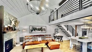 Ein modernes Wohnzimmer mit Kamin, einer Couch, einem Essbereich und einer Küche.