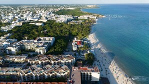 Luchtbeeld van een kustplaats met een strand, hotels en een mix van woon- en bedrijfsgebouwen.