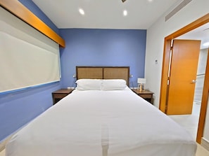 Ein Hotelzimmer mit einem Bett, einem Nachttisch, einer Lampe und einer Tür.