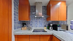 Een keuken met houten kastjes, een ingebouwde magnetron, een koffiezetapparaat en een waterdispenser.