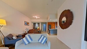 Een moderne woonkamer met een bank, een eethoek en een keuken op de achtergrond.
