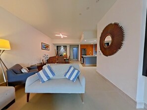 Ein modernes Wohnzimmer mit einer Couch, einem Essbereich und einer Küche im Hintergrund.