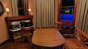 A dining area with a wooden table, chairs, a microwave, and a coffee maker.