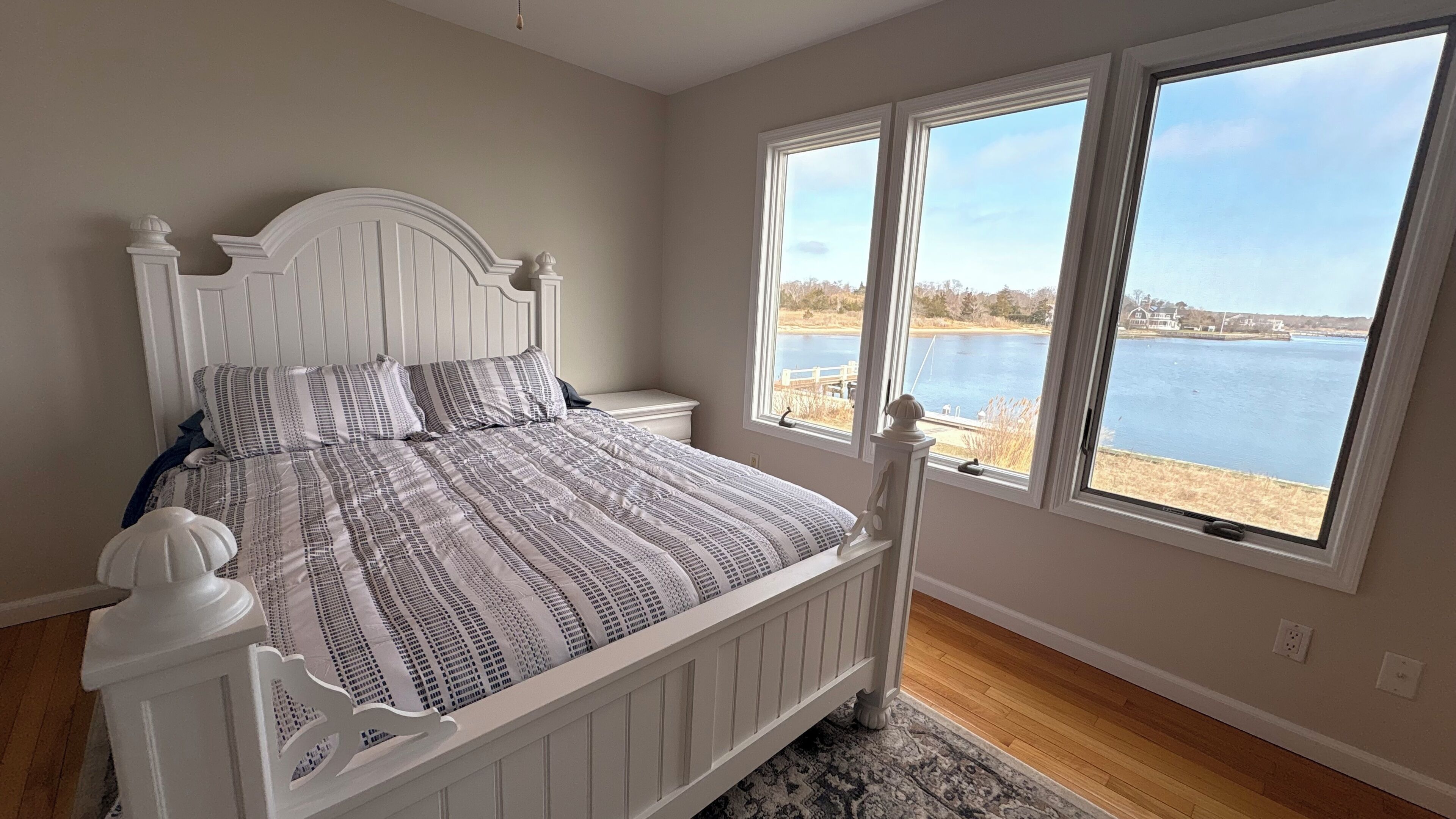 A bedroom with a bed, a view of a lake, and a window.