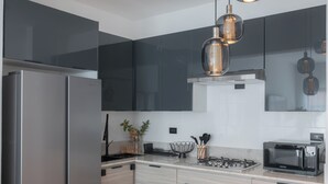 Een moderne keuken met roestvrijstalen apparatuur, een gasfornuis, een magnetron en hangende lampen.