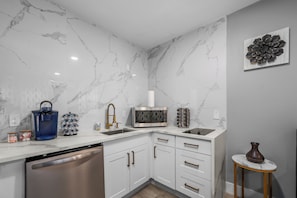 A modern kitchen with marble walls, white cabinets, and stainless steel appliances. - Retreat for Two: Spa Bath & King Suite in Montrose (Houston)