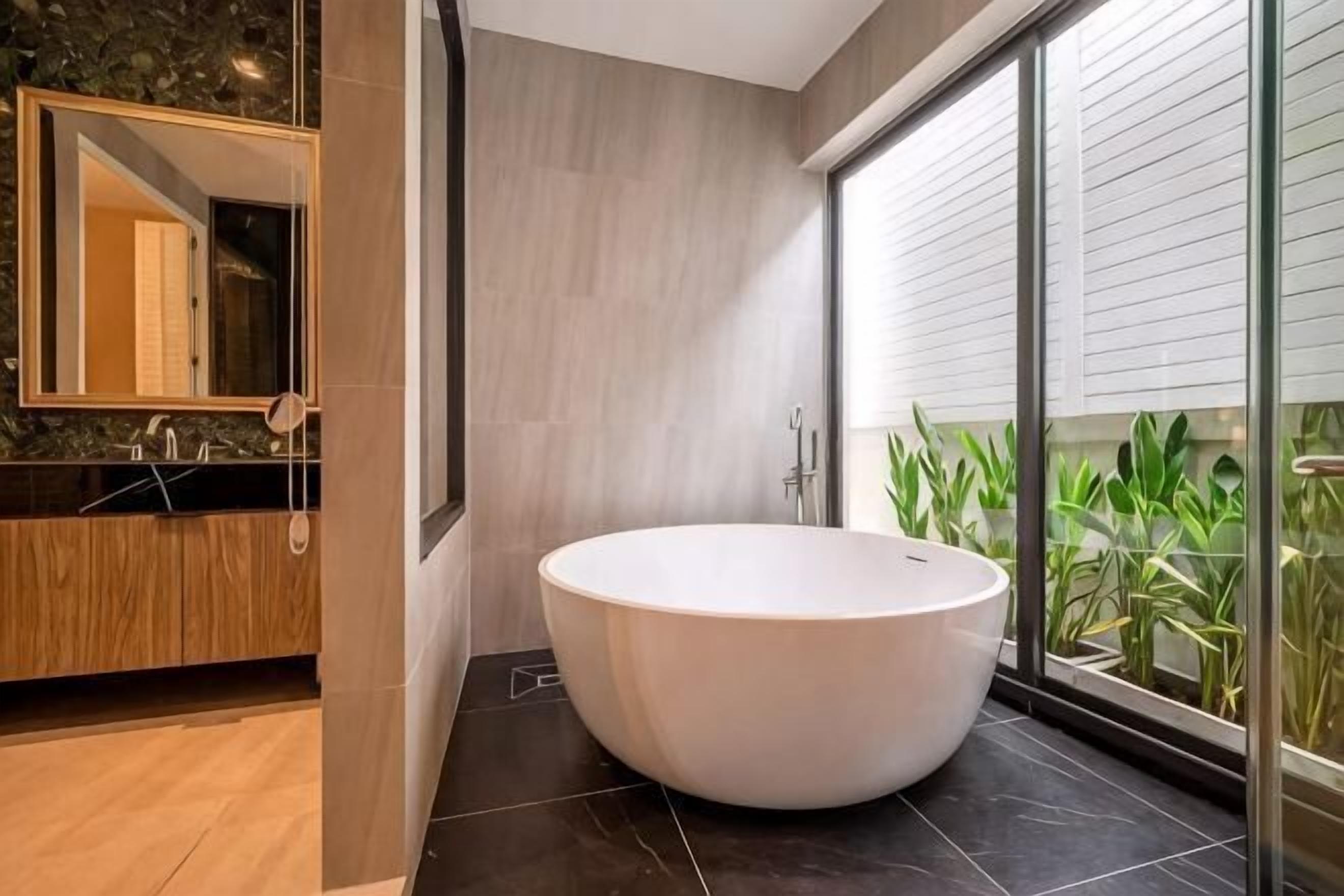 A modern bathroom with a freestanding bathtub, a wooden vanity, and a large mirror.