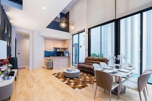 A modern living space with a dining area, a sofa, and a kitchen in the background. - Moon 5-Bedroom Luxury Pool Villa (Pattaya)