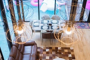 A modern interior with a dining area, a sofa, and a view through large windows. - Moon 5-Bedroom Luxury Pool Villa (Pattaya)