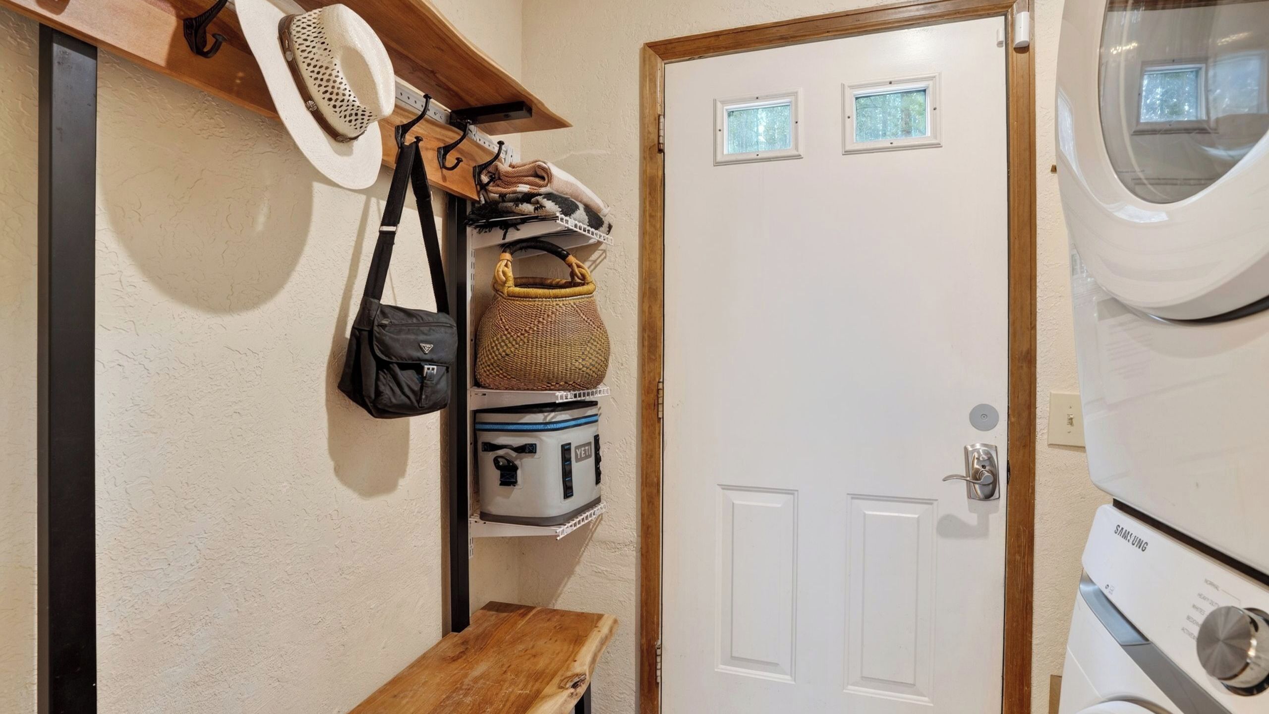 A laundry room with a washing machine, a dryer, and a door with small windows.